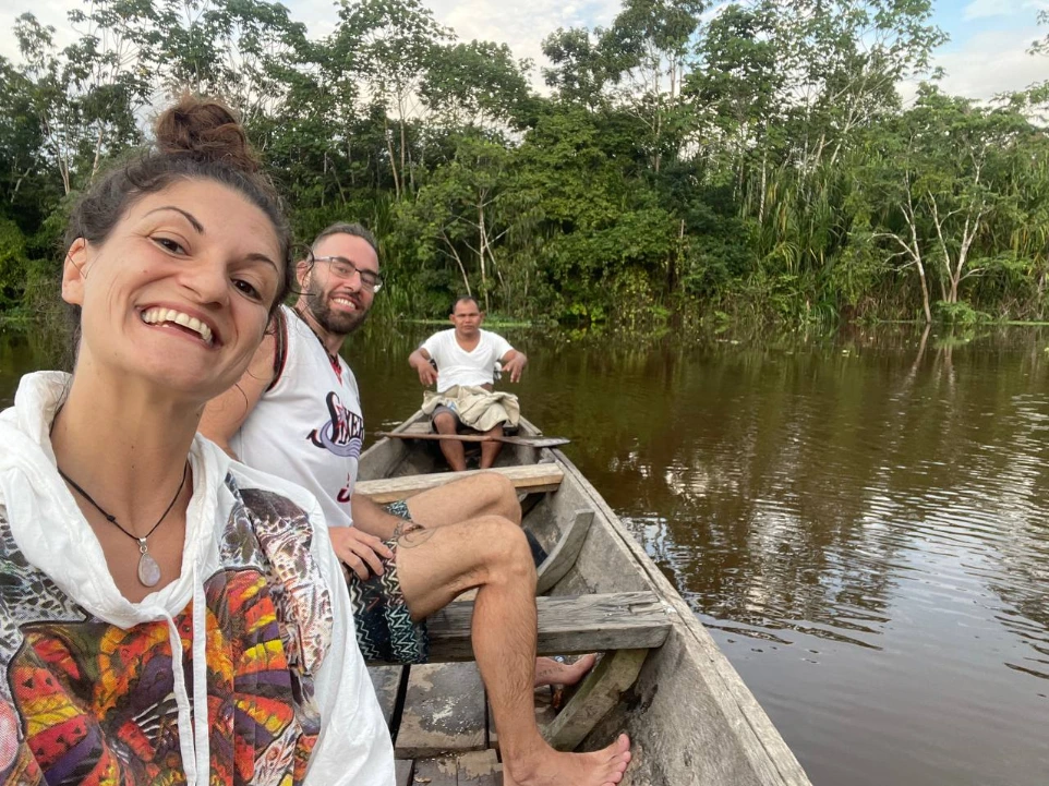 Dos turistas sonrientes disfrutando de una navegación en canoa de madera tradicional, guiada por un experto local, a través de las aguas tranquilas de la Reserva Nacional Pacaya Samiria.
