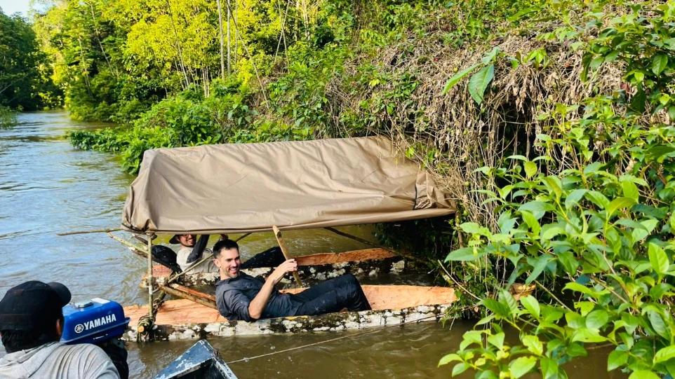 Tres hombres navegando por un afluente remoto del Amazonas en una canoa larga tallada a mano, durante una expedición de supervivencia de Ceiba Jungle Expeditions hacia la tribu Matsés.